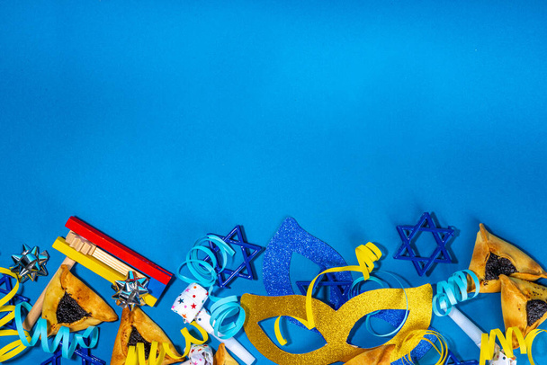   Vacaciones judías Purim tarjeta de felicitación fondo, comienzo de primavera judía carnaval plano de vacaciones con máscaras de carnaval tradicionales, sonajero, regalos y hamantaschen galleta sobre fondo colorido - Foto, imagen