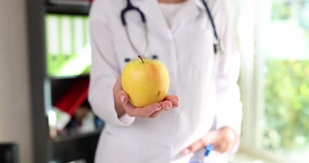 Κίτρινο φρέσκο μήλο στο χέρι του γιατρού γυναίκα, closeup. Έννοια υγιεινής διατροφής και διατροφής - Πλάνα, βίντεο