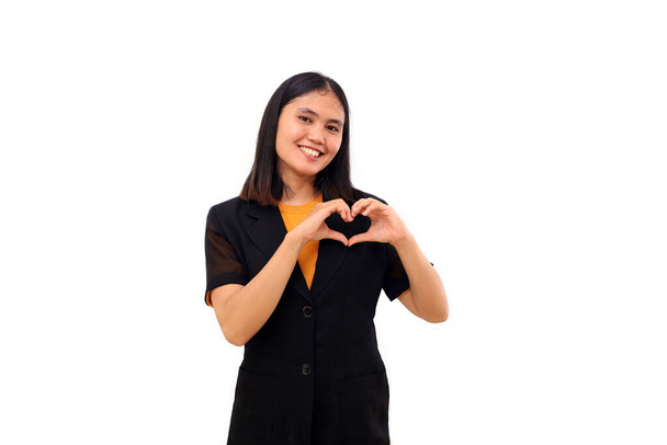 Happy young asian business woman making love heart hand shape and put it near chest. Isolated - Zdjęcie, obraz