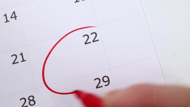 Kalendář zobrazující číslo 22 s mužskou rukou kroužící kolem data s červeným perem, uložit datum nebo připomenutí události koncept. - Záběry, video