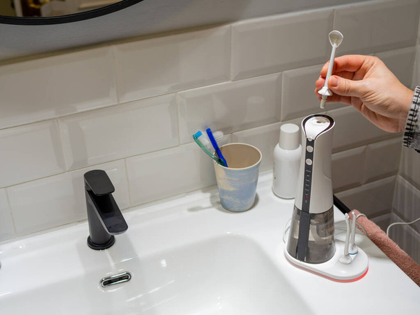 Joven manos cambiando su agua dental doméstica punta del hilo dental - Foto, Imagen