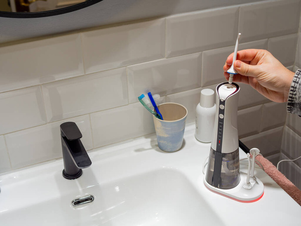  Joven mujer manos cambiando su agua dental doméstica punta del hilo dental - Foto, Imagen