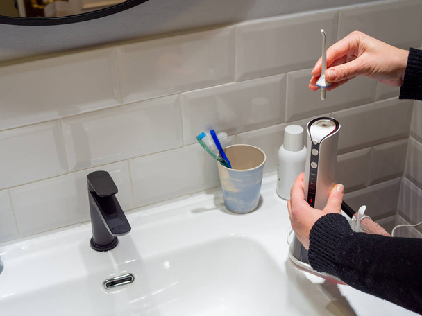  Joven mujer manos cambiando su agua dental doméstica punta del hilo dental - Foto, Imagen
