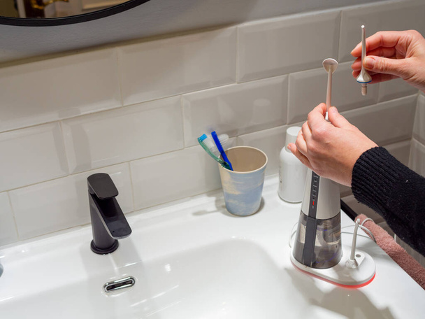  Młoda kobieta ręce zmieniając jego domowej wody dentystycznej końcówki nici dentystycznej - Zdjęcie, obraz