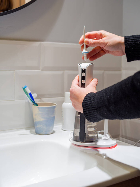  Молодая женщина руки изменения его домашней зубной воды зубной нитью наконечник - Фото, изображение