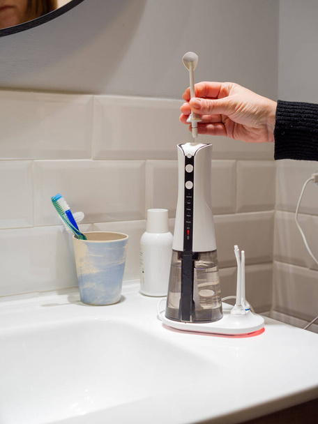  Young woman hands changing his domestic dental water flosser tip - Fotó, kép