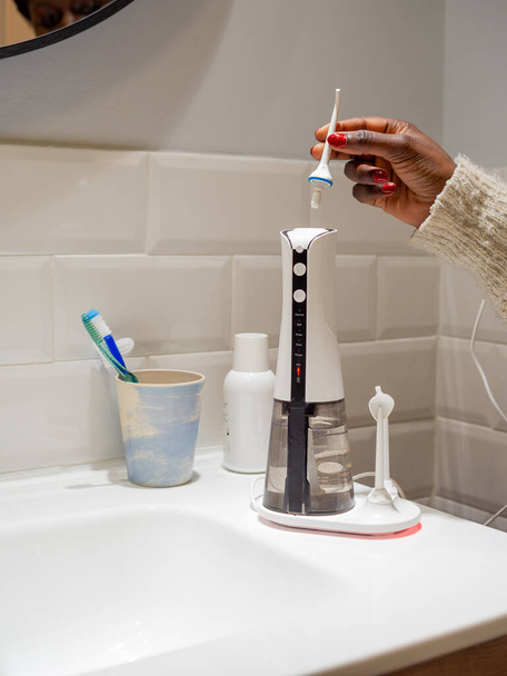  Νεαρή γυναίκα αλλάζει το οικιακό οδοντικό νήμα νερού άκρη του - Φωτογραφία, εικόνα