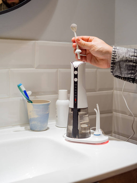 Young man hands changing his domestic dental water flosser tip - Foto, immagini