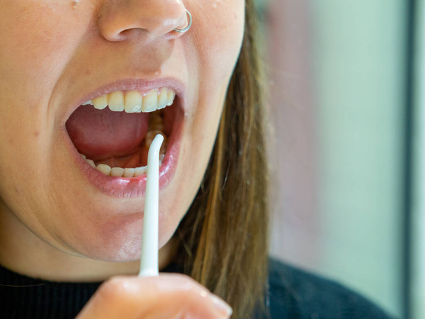  Healthy Oral Hygiene: Young woman Using domestic dental water flosser - Фото, изображение