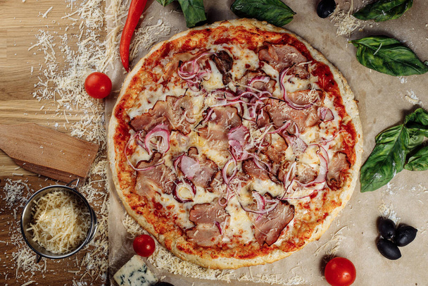 Pizza con queso de pollo y pepperoni, un trozo de la cual se corta y se coloca como un pakman, está sobre una tabla de madera y un fondo marrón. El queso esparce vetas fluidas. Foto de alta calidad - Foto, imagen