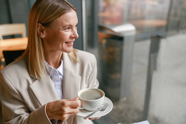 Businesswoman having coffee break time during working day in cafe. Distance work concept - Foto, Bild