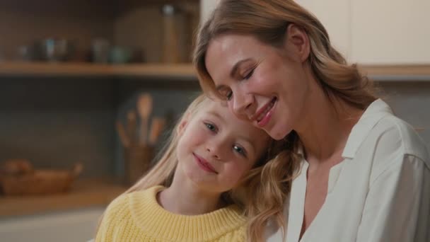 Portrait Caucasian preschool cute affectionate adopted little girl child daughter schoolgirl hugging foster cuddle care mother with eyes cuddling mum cuddling kid enjoy tender sweet moment at kitchen - Materiał filmowy, wideo