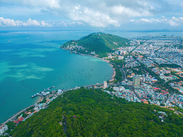 Vung Tau city aerial view with beautiful sunset and so many boats. Panoramic coastal Vung Tau view from above, with waves, coastline, streets, coconut trees and Tao Phung mountain in Vietnam. - 写真・画像