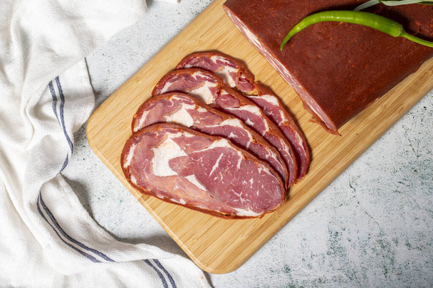 Beef ribeye pastrami. Dried turkish bacon slice on wooden Cutting Board. Traditional Turkish delicacies. Top view. Local name cemenli pastirma - Photo, Image