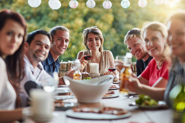 Good food brought us together. Portrait of a group of happy young friends sharing a meal at a backyard dinner party - Foto, Imagem