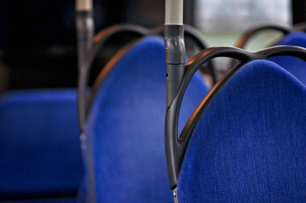 Világos kék ülések egy buszon, fekete-fém részletekkel. Fekete fogantyúk a kék üléseken, üres buszon, emberek nélkül. Buszútra indul, finn tömegközlekedéssel. - Fotó, kép