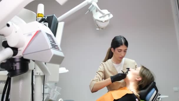 女性歯科医は、現代の歯科事務所で患者の口腔を検査します。歯医者による健康診断 - 映像、動画