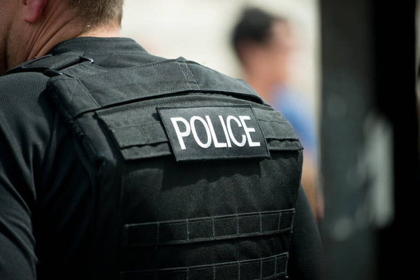 Whitehall, Λονδίνο, Ηνωμένο Βασίλειο. 16 Ιουλίου 2016. Αστυνομικό έμπλαστρο λογότυπου, που φοριέται στο πίσω μέρος αλεξίσφαιρου γιλέκου από Μητροπολίτη στο κεντρικό Λονδίνο, Ηνωμένο Βασίλειο. - Φωτογραφία, εικόνα