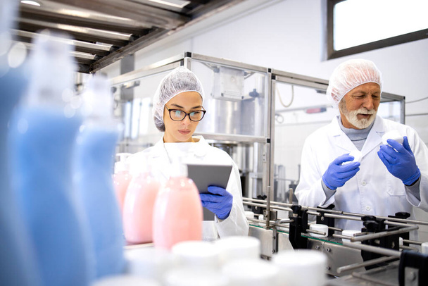 Cosmetics production and workers standing by machine doing quality control of cleaning chemicals. - Photo, Image