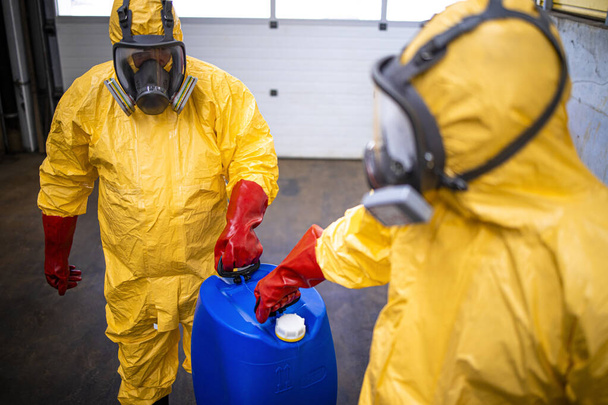 Trabalhadores da indústria em trajes de proteção manuseando ácidos e substâncias agressivas na fábrica de produção de produtos químicos. - Foto, Imagem