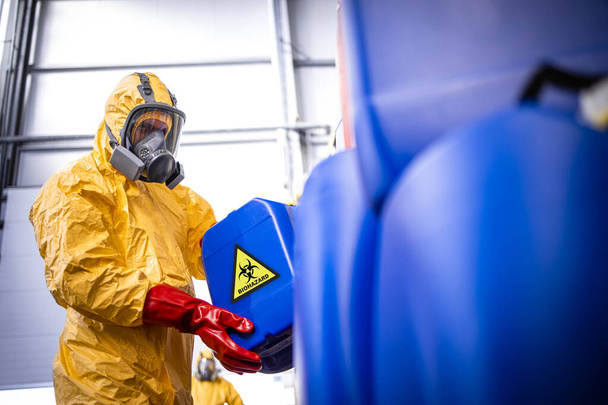 Gaz maskesi ve koruyucu elbisesi olan fabrika işçisi zehirli ve tehlikeli kimyasallarla çalışıyor.. - Fotoğraf, Görsel