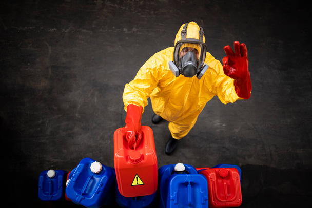 Professional worker in hazmat protection suit and gas mask working with dangerous chemicals inside factory. - Foto, Imagen