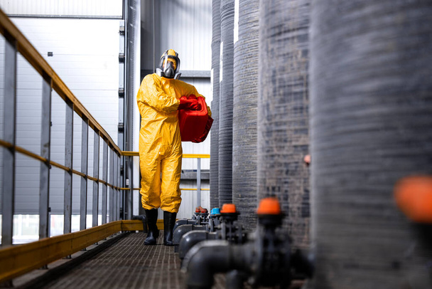Промисловий працівник у захисному обладнанні та газовій масці, що працює на хімічному заводі
. - Фото, зображення