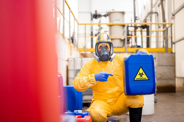 Recycling plant worker in protection suit and gas mask disposing biohazard and toxic material. - Foto, Imagen