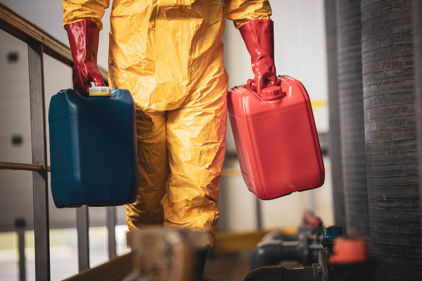 Onherkenbare chemicaliënwerker met plastic bussen in fabriek. - Foto, afbeelding