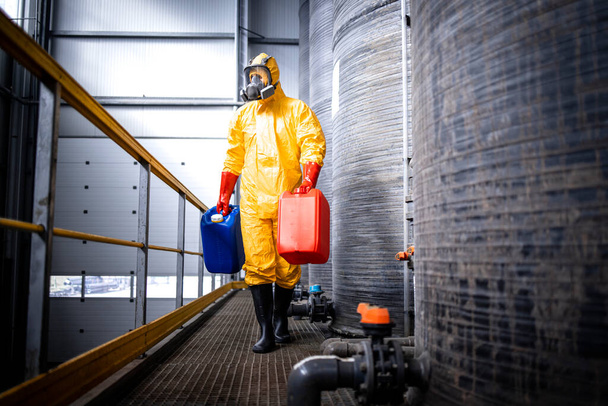 Worker carrying canisters in chemicals production plant. - Foto, Imagen
