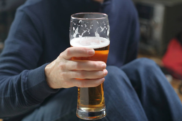 a person holds a mug with beer in his right hand in front of him - Photo, Image