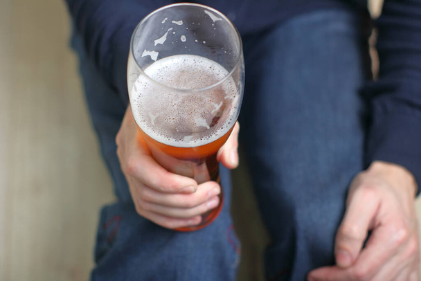 a person holds a mug with beer in his right hand in front of him - Foto, imagen
