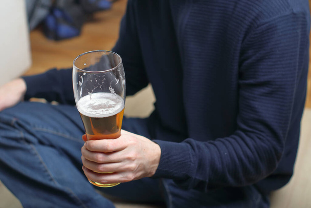 uma pessoa segura uma caneca com cerveja na mão esquerda na frente dele - Foto, Imagem