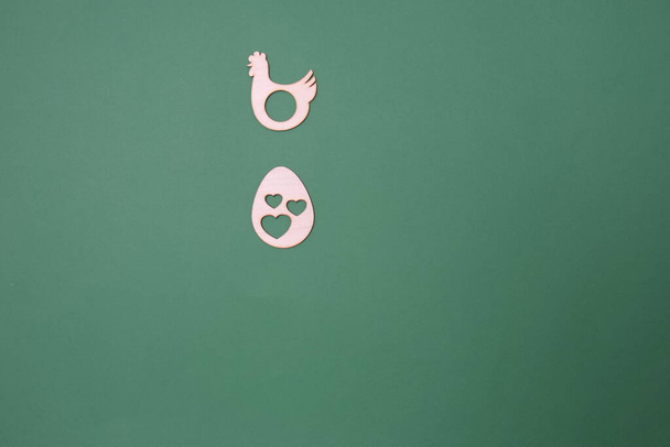 A laying hen and an egg with hearts on a green background with copy space. Minimal flat lay Easter scene. - Foto, Imagem