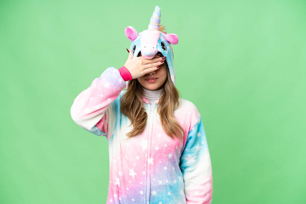 Chica joven con pijama de unicornio sobre fondo de croma clave aislada que cubre los ojos por las manos. No quiero ver algo. - Foto, imagen
