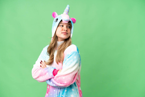 Chica joven con pijama de unicornio sobre fondo de croma clave aislado con los brazos cruzados y feliz - Foto, Imagen