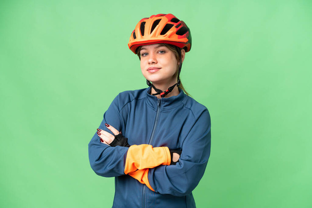 Young cyclist girl over isolated chroma key background keeping the arms crossed in frontal position - Foto, immagini