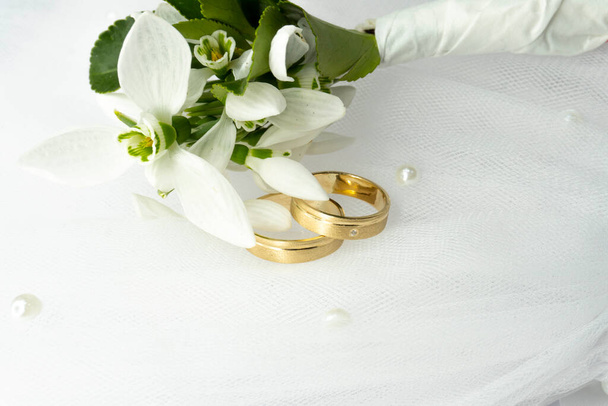 Bagues de mariage or et fleurs de chute de neige - Photo, image