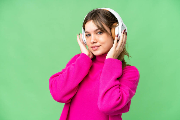 Chica joven sobre aislado croma clave fondo escuchar música - Foto, Imagen
