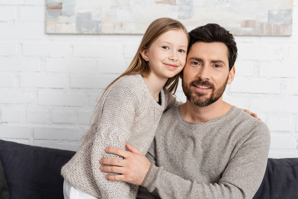 bearded man and preteen girl smiling and looking at camera at home - Fotoğraf, Görsel
