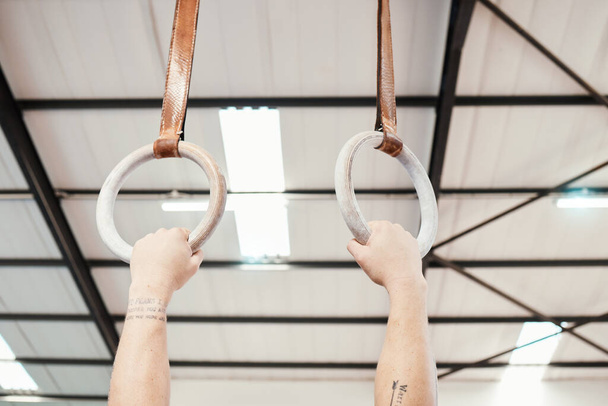 Hands, rings and gymnastics in fitness for workout, strength training or practice at gym. Hand of athlete, gymnast or acrobat holding or hanging on ring circles for strong intense pull up exercise. - Foto, immagini