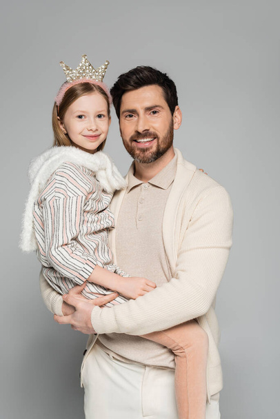 happy father lifting cheerful daughter in crown and dress isolated on grey  - Zdjęcie, obraz