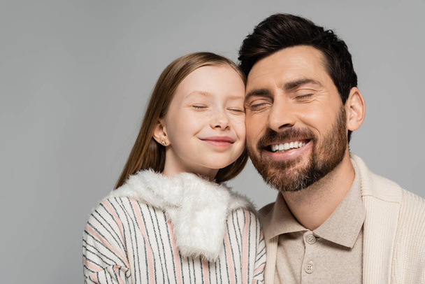 portret van vrolijke vader en dochter glimlachend met gesloten ogen geïsoleerd op grijs  - Foto, afbeelding
