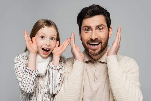 portrait of amazed father and daughter gesturing and looking at camera isolated on grey  - Foto, Imagem