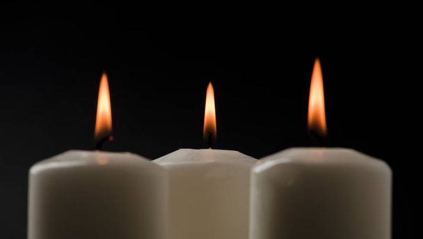 three burning candles on white table with black background, space for text - Foto, Imagen