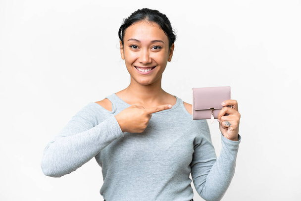Young Uruguayan woman holding a wallet over isolated white background and pointing it - Fotoğraf, Görsel