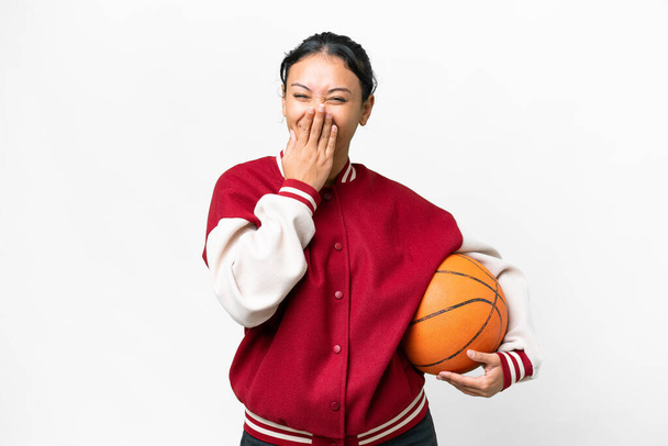 Young Uruguayan woman playing basketball over isolated wall  over isolated white background happy and smiling covering mouth with hand - Φωτογραφία, εικόνα