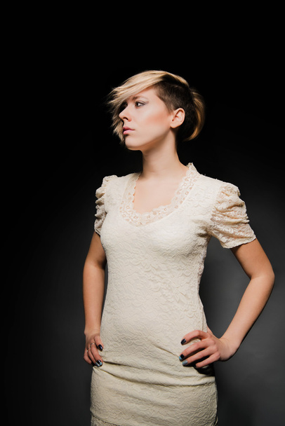 Blonde girl with a short stylish haircut on a dark background - Foto, Imagen