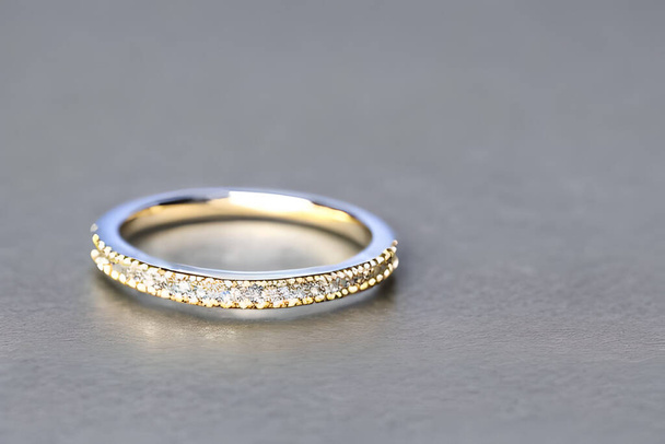 愛とコミットメントの永遠の絆を象徴するために繊細に絡み合って、単一の結婚指輪の見事なクローズアップショット。記念日、バレンタイン、または婚約のためのジュエリーゴールドダイヤモンドリング - 写真・画像