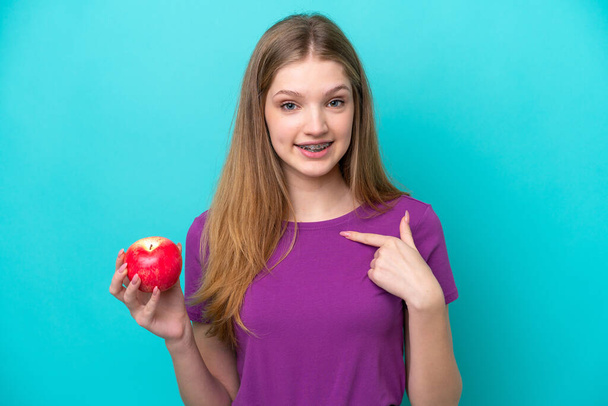 teenager girl holding apple isolated with blue background  - Photo, Image